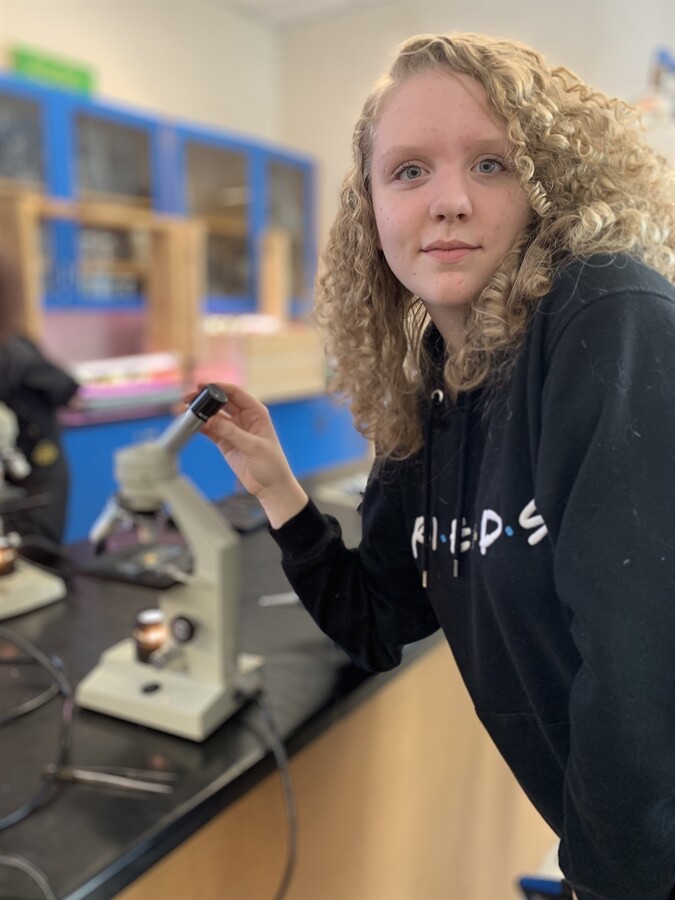 picture of a student looking through a microscope