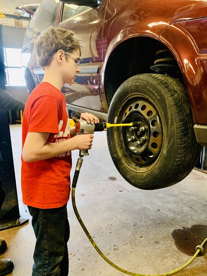 picture of a student putting a tire on a car