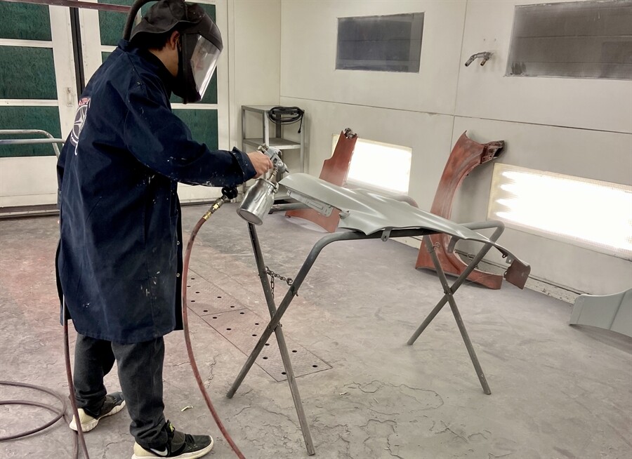 picture of a student painting a side panel of a car