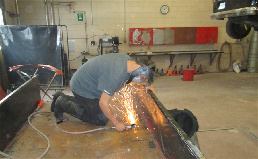 student grinding a piece of a car