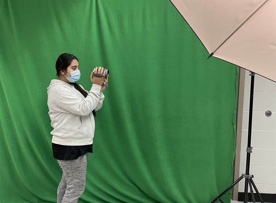 A picture of a student with a green screen behind them