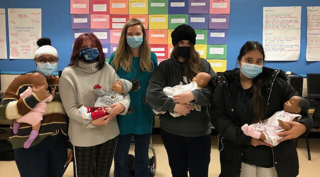 a group of people holding baby dolls