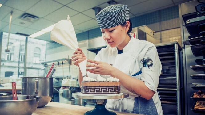 Student putting icing on a cake